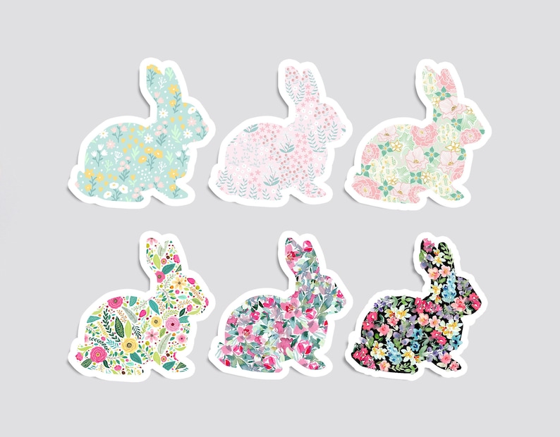 May include: Six colorful bunny rabbit silhouettes with floral patterns. The bunnies are in various colors, including pink, blue, green, and black. Each bunny has a different floral pattern.