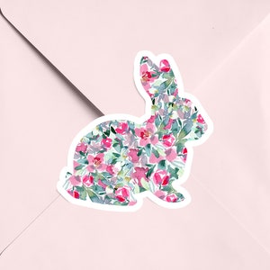 May include: A white silhouette of a rabbit filled with a watercolor pattern of pink and green flowers.
