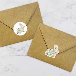 May include: Two brown envelopes with white round stickers featuring a floral bunny design. The bunny is outlined in black and filled with a pattern of pink, yellow, and green flowers.