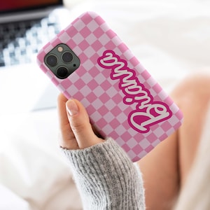 May include: Pink and white checkered phone case with the word "Barbie" in pink lettering.