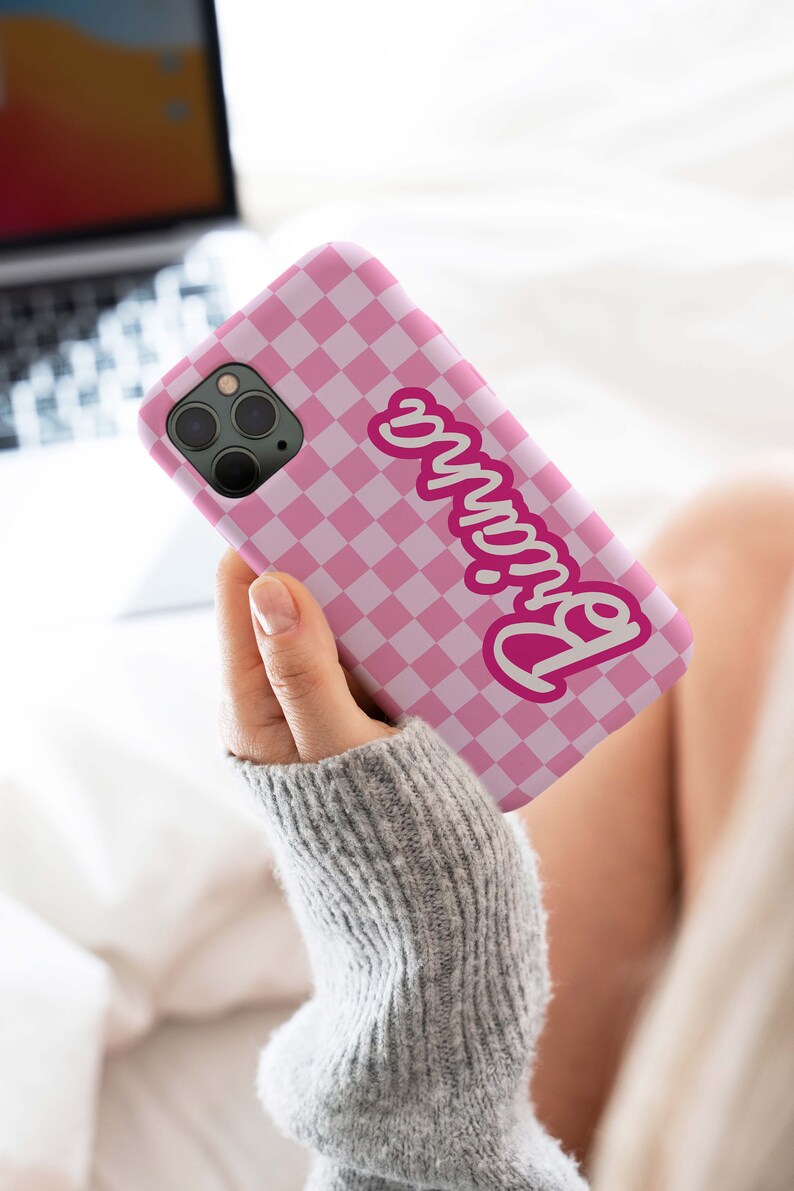 May include: Pink and white checkered phone case with the word "Barbie" in pink lettering.