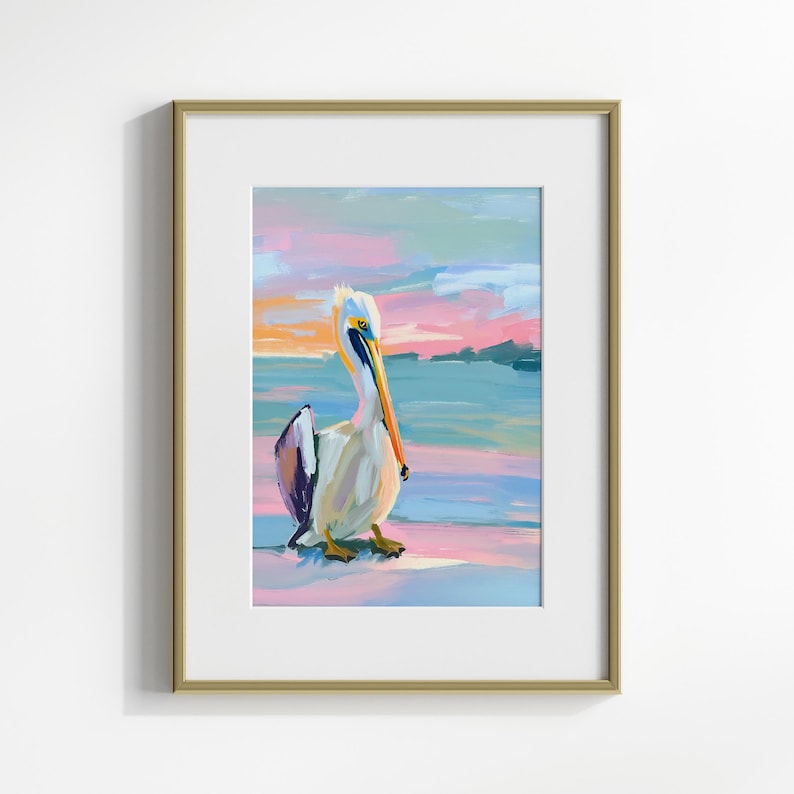 May include: A framed painting of a pelican standing on a beach at sunset. The pelican is white with a long orange beak and blue and purple accents. The background is a soft pink and blue.