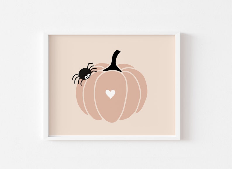 May include: A pink pumpkin with a black spider on the side and a white heart in the center. The pumpkin is on a light pink background.