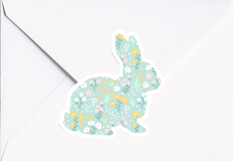 May include: A light blue bunny silhouette sticker with a floral pattern. The pattern includes white, pink, yellow, and green flowers on a light blue background.
