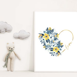 May include: A framed art print featuring a watercolor floral heart design in yellow and blue, with the word "love" in gold script. Decorative clouds and a crocheted bear are also in the image.