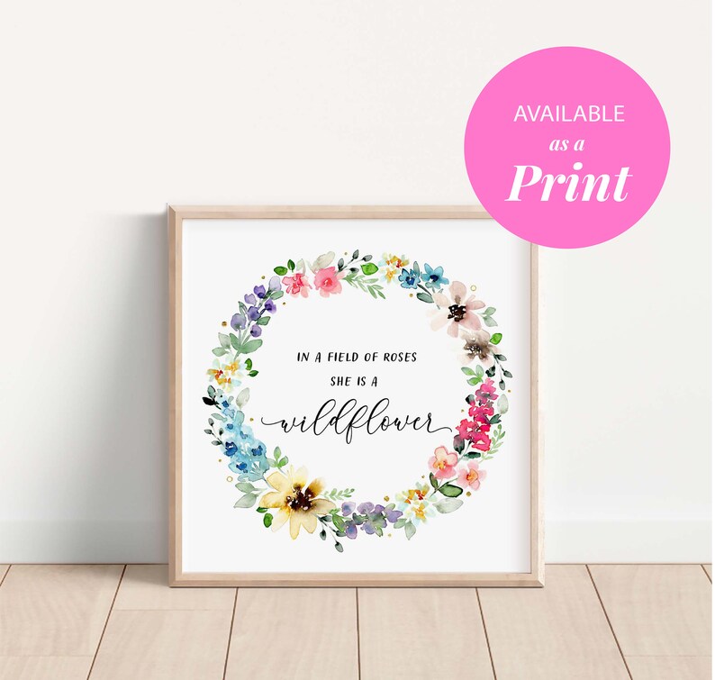 May include: A watercolor print with a floral wreath and the text "In a field of roses she is a wildflower".