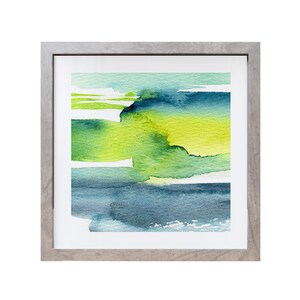 May include: Abstract watercolor painting in a gray frame. The painting features shades of green, blue, and yellow, creating a layered and textured effect.