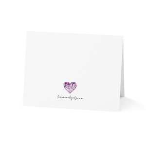 May include: A white card with a purple heart filled with white flowers and the text "love more by design".