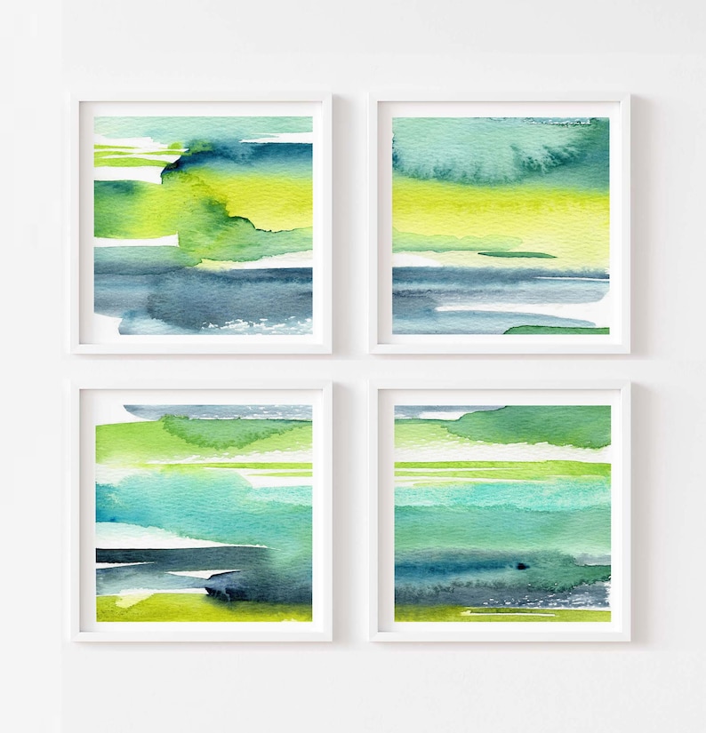 May include: Set of four abstract watercolor paintings in shades of green, blue, and yellow. The paintings are framed in white and hung on a white wall.