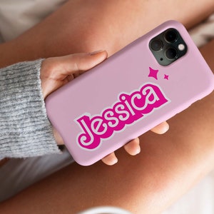 May include: A pink phone case with a pink and white design. The name "Jessica" is written in a retro font with white outlines. Two small white stars are above the name.
