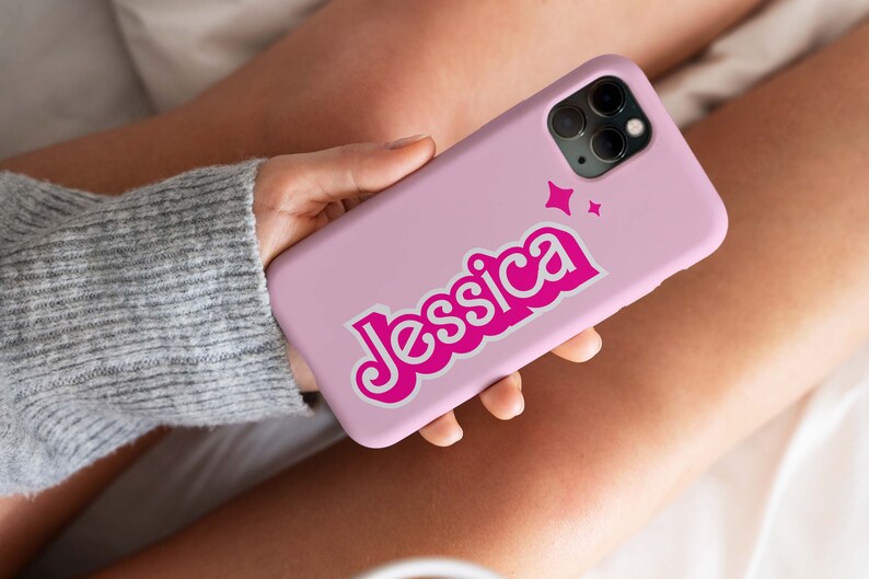 May include: A pink phone case with a pink and white design. The name "Jessica" is written in a retro font with white outlines. Two small white stars are above the name.