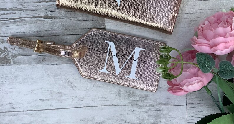 Pu&ograve; includere: Etichetta per bagagli in oro rosa con una M bianca e il nome Maria scritto in corsivo.
