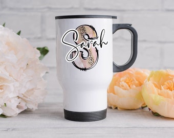 Può includere: Tazza da viaggio bianca con coperchio e manico neri. La tazza ha un design rosa e oro con il nome "Sarah" scritto in corsivo nero.