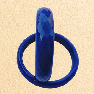 May include: Two blue plastic bangles, one with a textured diamond pattern and the other smooth. The bangles are stacked on top of each other.