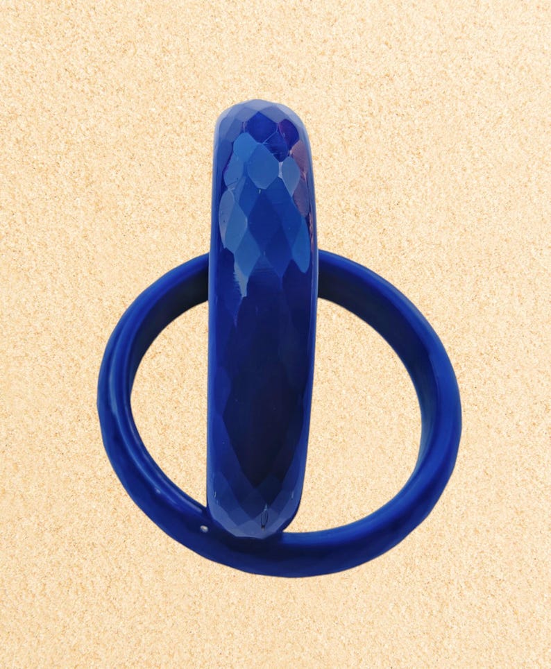 May include: Two blue plastic bangles, one with a textured diamond pattern and the other smooth. The bangles are stacked on top of each other.