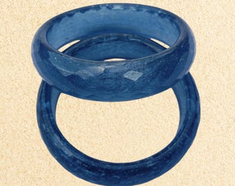 May include: Two blue resin bangle bracelets stacked on top of each other. The bracelets have a textured, slightly rough surface.