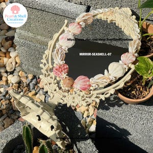 Könnte beinhalten: Ovaler Muschelspiegel mit cremefarbenem Rahmen. Der Spiegel ist mit verschiedenen Muscheln in Rosa, Weiß und Beige verziert, akzentuiert mit kleinen Perlen. Der Text "MIRROR-SEASHELL-07" ist auf dem Spiegel sichtbar.