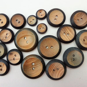 May include: Assortment of wooden buttons with a dark brown rim and a light brown centre. The buttons have two holes and are various sizes.