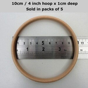May include: A wooden embroidery hoop with a diameter of 4 inches or 10 centimeters. The hoop is 1 centimeter deep. The hoop is shown next to a ruler.