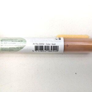 May include: A close-up of a gold cosmetic tube with the text "Art No. 39852 Color: Gold" and a barcode. The tube is made in China.