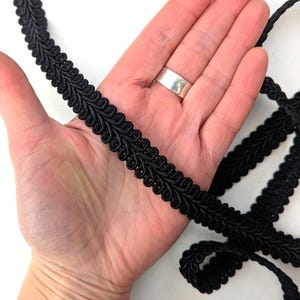 Puede incluir: Borde trenzado negro con un patrón de hoja decorativo. El borde tiene aproximadamente 2,5 cm de ancho.