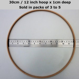 May include: A 12 inch wooden embroidery hoop with a 1 cm depth. The hoop is being measured with a ruler.  30cm / 12 inch hoop x 1cm deep Sold in packs of 3 to 5