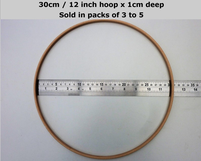 May include: A 12 inch wooden embroidery hoop with a 1 cm depth. The hoop is being measured with a ruler.  30cm / 12 inch hoop x 1cm deep Sold in packs of 3 to 5