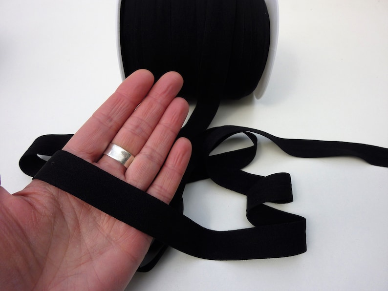 Puede incluir: Cinta el&aacute;stica negra, de aproximadamente 2,5 cm de ancho, mostrada en una mano. La cinta es suave y flexible, y es ideal para proyectos de costura.