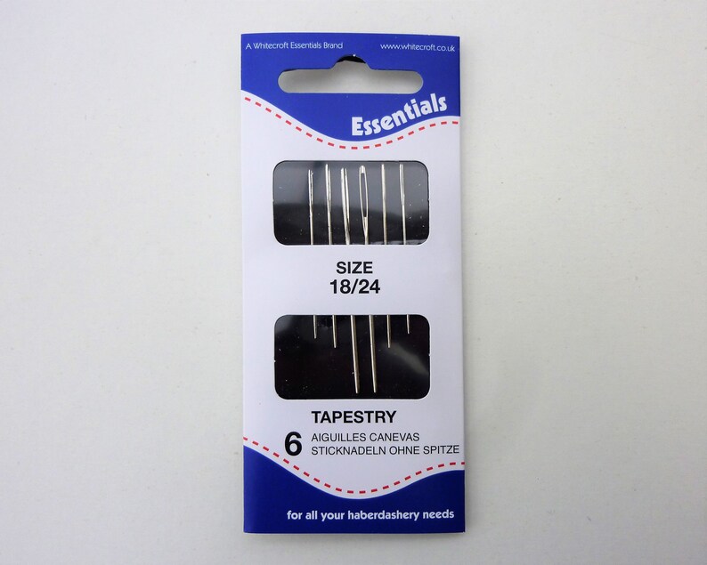 May include: A package of 6 tapestry needles, size 18/24, in a blue and white package with the text "Essentials" and "TAPESTRY" printed on it.