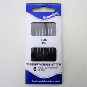 May include: A package of 6 tapestry needles, size 26, for cross stitch. The needles are silver and come in a blue and white package with the text "Essentials" and "Tapestry/Cross Stitch".
