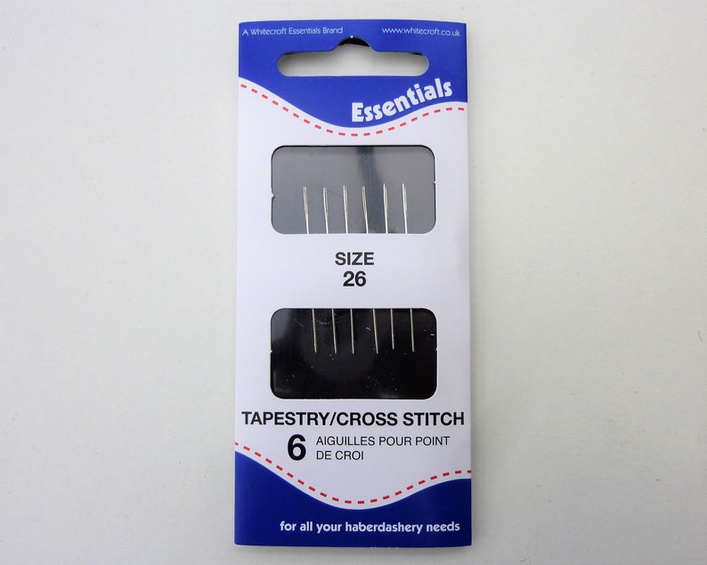 May include: A package of 6 tapestry needles, size 26, for cross stitch. The needles are silver and come in a blue and white package with the text "Essentials" and "Tapestry/Cross Stitch".