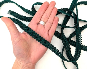 May include: Green braided trim with a leaf design. The trim is approximately 1 inch wide.