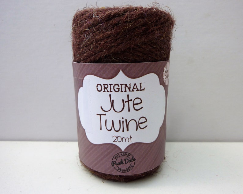 May include: A roll of brown jute twine with a white label that says "ORIGINAL Jute Twine 20mt" and a logo that says "Peak Dale Products".