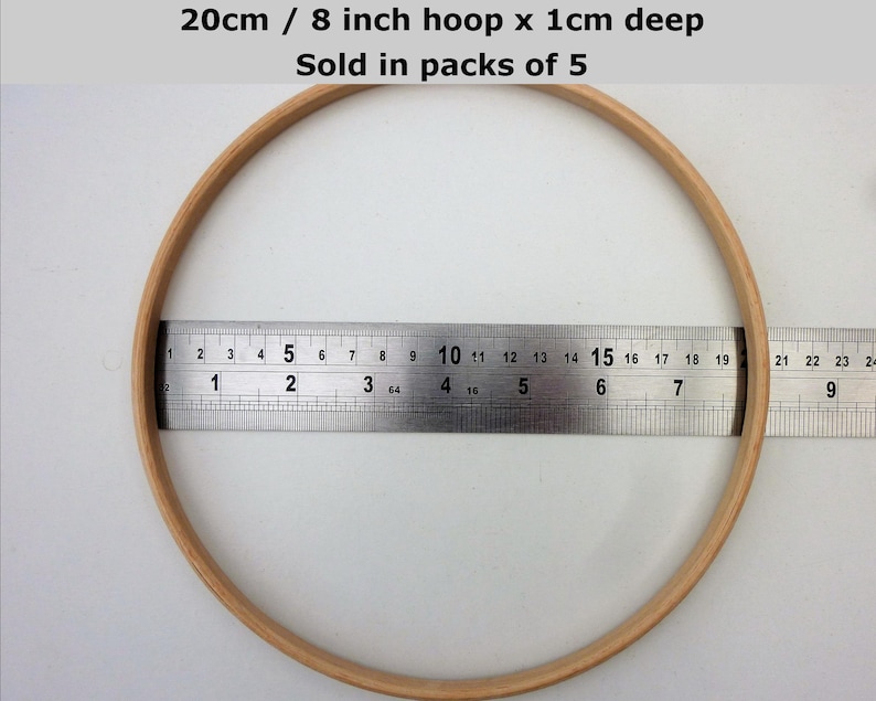 May include: A wooden embroidery hoop with a diameter of 8 inches or 20 centimeters. The hoop is 1 centimeter deep. The hoop is being measured with a ruler. The text on the image reads "20cm / 8 inch hoop x 1cm deep Sold in packs of 5".