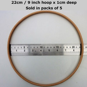 May include: A 9 inch embroidery hoop with a 1 inch depth. The hoop is made of natural wood and is 22 cm in diameter. It is shown next to a ruler for size reference.  Sold in packs of 5.