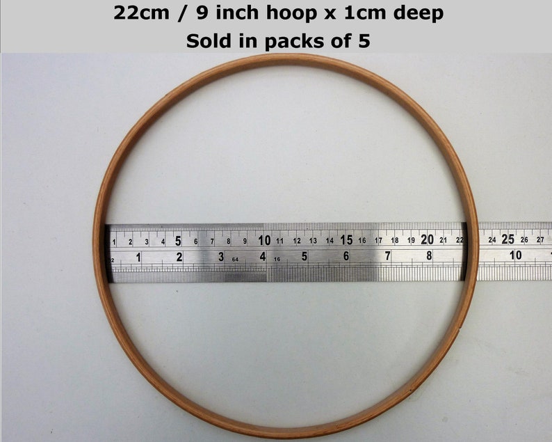 May include: A 9 inch embroidery hoop with a 1 inch depth. The hoop is made of natural wood and is 22 cm in diameter. It is shown next to a ruler for size reference.  Sold in packs of 5.