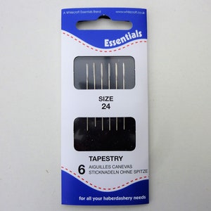 May include: A package of 6 tapestry needles, size 24, in a blue and white package with the text "Essentials" and "TAPESTRY" on it. The package also includes the text "AIGUILLES CANEVAS" and "STICKNADELN OHNE SPITZE".