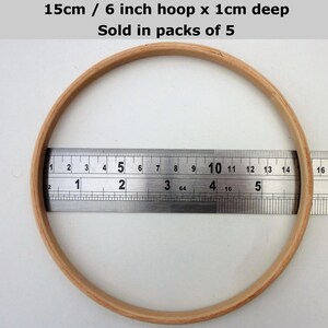May include: A wooden embroidery hoop with a diameter of 6 inches or 15 centimeters. The hoop is 1 centimeter deep. The hoop is being measured with a ruler.
