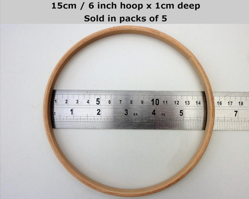 May include: A wooden embroidery hoop with a diameter of 6 inches or 15 centimeters. The hoop is 1 centimeter deep. The hoop is being measured with a ruler.