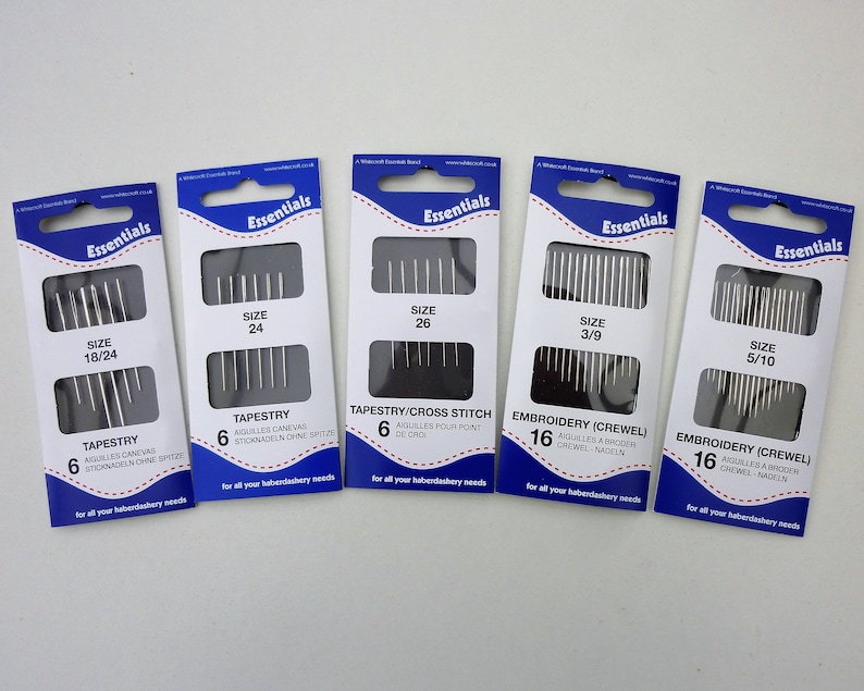 May include: Six packages of needles for tapestry and embroidery. The packages are labeled with the size of the needles and the type of needle. The needles are silver and come in packs of 6 or 16.