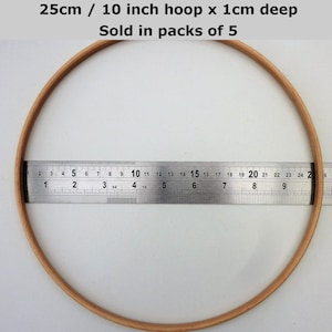 May include: A 10 inch wooden embroidery hoop with a 1 cm depth. The hoop is measured with a ruler. The text "25cm / 10 inch hoop x 1cm deep Sold in packs of 5" is visible at the top of the image.