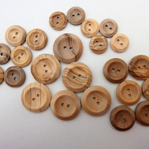 May include: A collection of wooden buttons in various sizes and shades of brown. The buttons have a natural wood grain pattern and two holes for sewing.