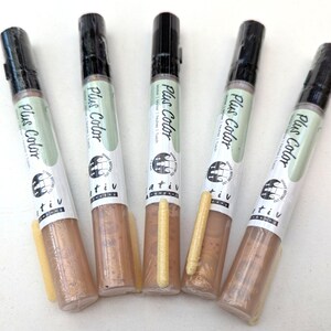 May include: Five gold metallic paint markers with black caps and a white label that says "Plus Color" and "tiv".