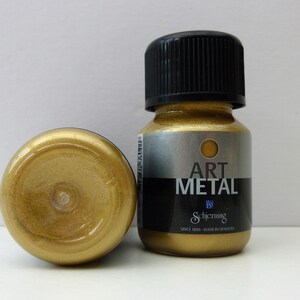 K&ouml;nnte beinhalten: Eine kleine Flasche goldfarbener Metallic-Farbe mit der Aufschrift "Art Metal" von Schjerning. Die Flasche wird in D&auml;nemark hergestellt und ist Teil der Schjerning Art Metal-Farbenlinie.