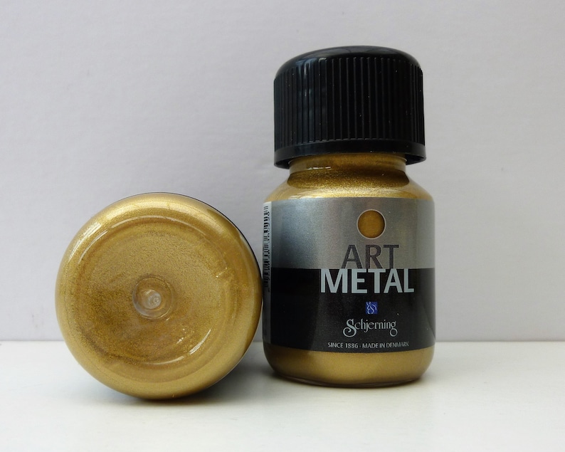 K&ouml;nnte beinhalten: Eine kleine Flasche goldfarbener Metallic-Farbe mit der Aufschrift "Art Metal" von Schjerning. Die Flasche wird in D&auml;nemark hergestellt und ist Teil der Schjerning Art Metal-Farbenlinie.