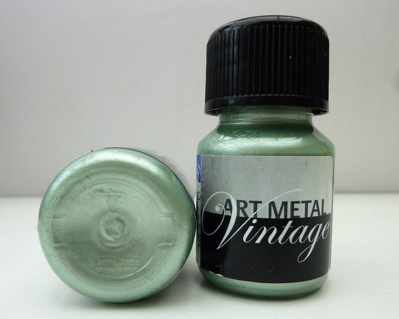 K&ouml;nnte beinhalten: Zwei Flaschen metallisch gr&uuml;ner Farbe mit schwarzem Deckel und einem Etikett mit der Aufschrift "Art Metal Vintage".