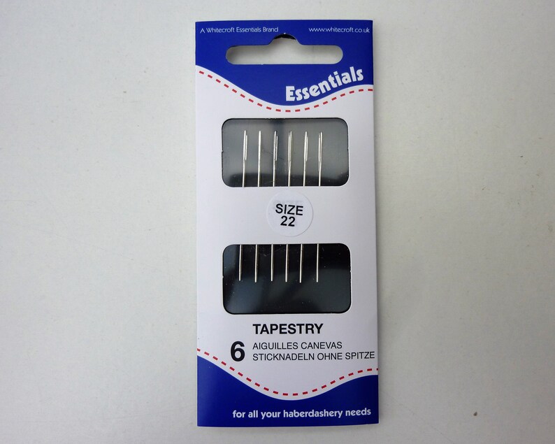 May include: A package of 6 tapestry needles, size 22, in a blue and white package with the text "Essentials" and "Tapestry" on it.