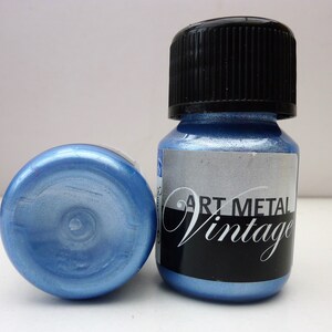 K&ouml;nnte beinhalten: Zwei kleine Flaschen mit blauer Metallic-Farbe und schwarzen Deckeln. Das Etikett auf einer Flasche lautet "Art Metal Vintage".
