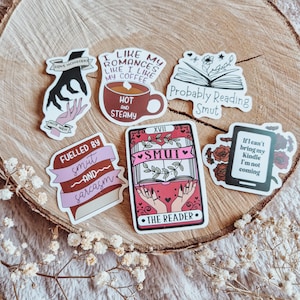 Könnte beinhalten: Eine Sammlung von Aufklebern mit verschiedenen Designs und Texten. Ein Aufkleber zeigt eine Kaffeetasse mit "Hot and Steamy". Ein anderer sagt "Probably Reading Smut". Weitere Aufkleber sind "Love Monsters", "Fuelled by smut and sarcasm" und "The Reader".