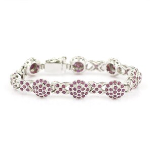 May include: A silver bracelet with a delicate chain design and round pink gemstones. The bracelet has a clasp closure.